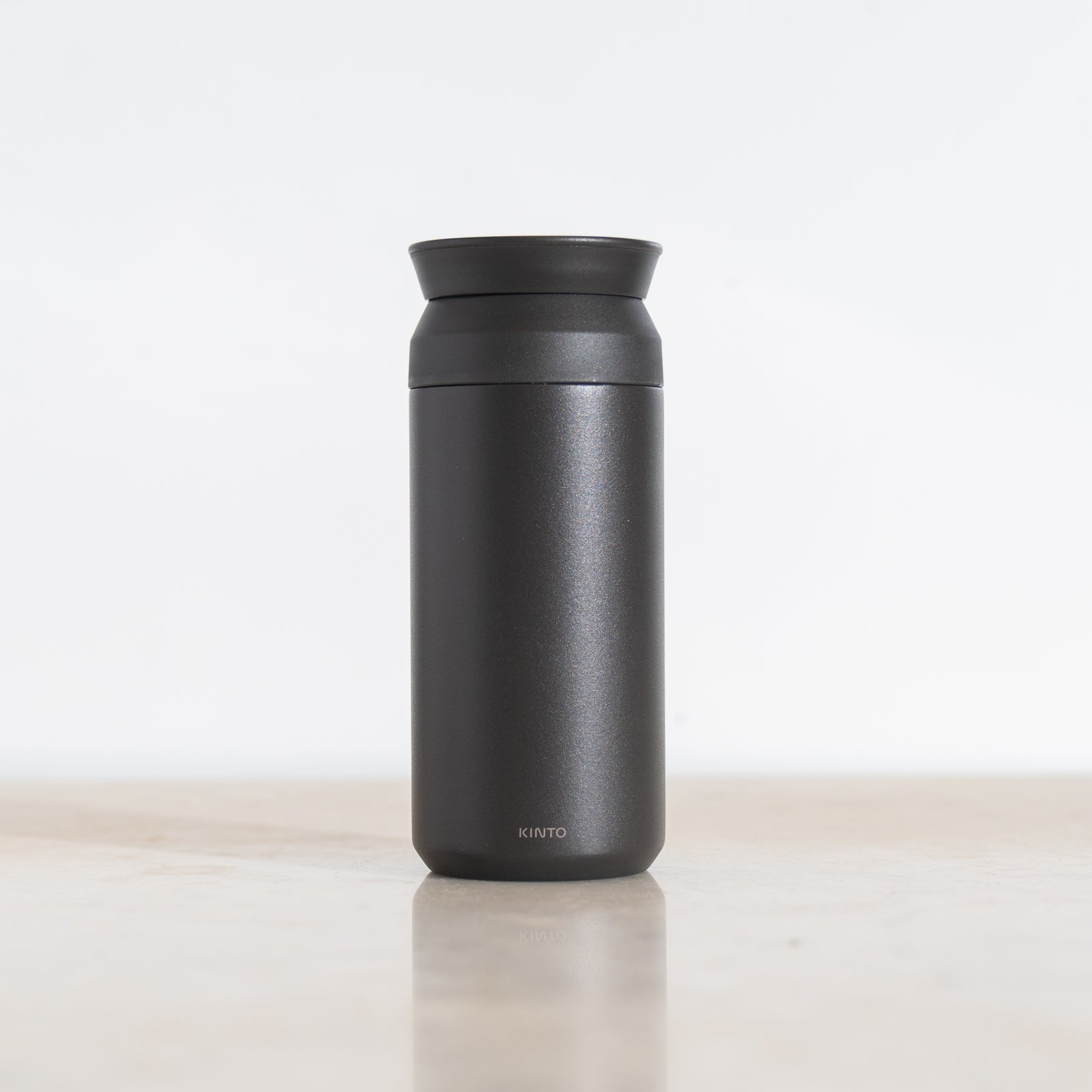 Black Kinto thermos with black lid on a light beige surface