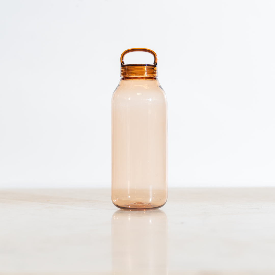 Clear amber tinted plastic water bottle with a gold cap on a white background