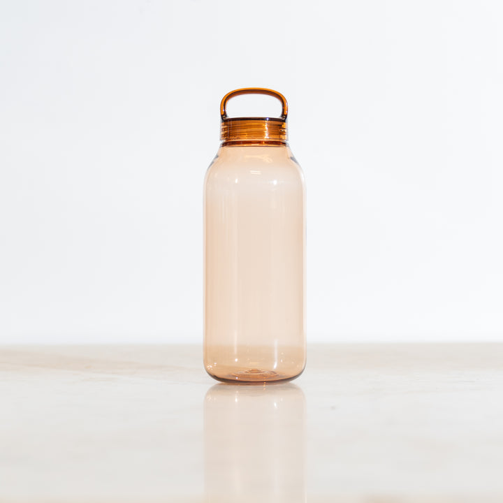 Clear amber tinted plastic water bottle with a gold cap on a white background