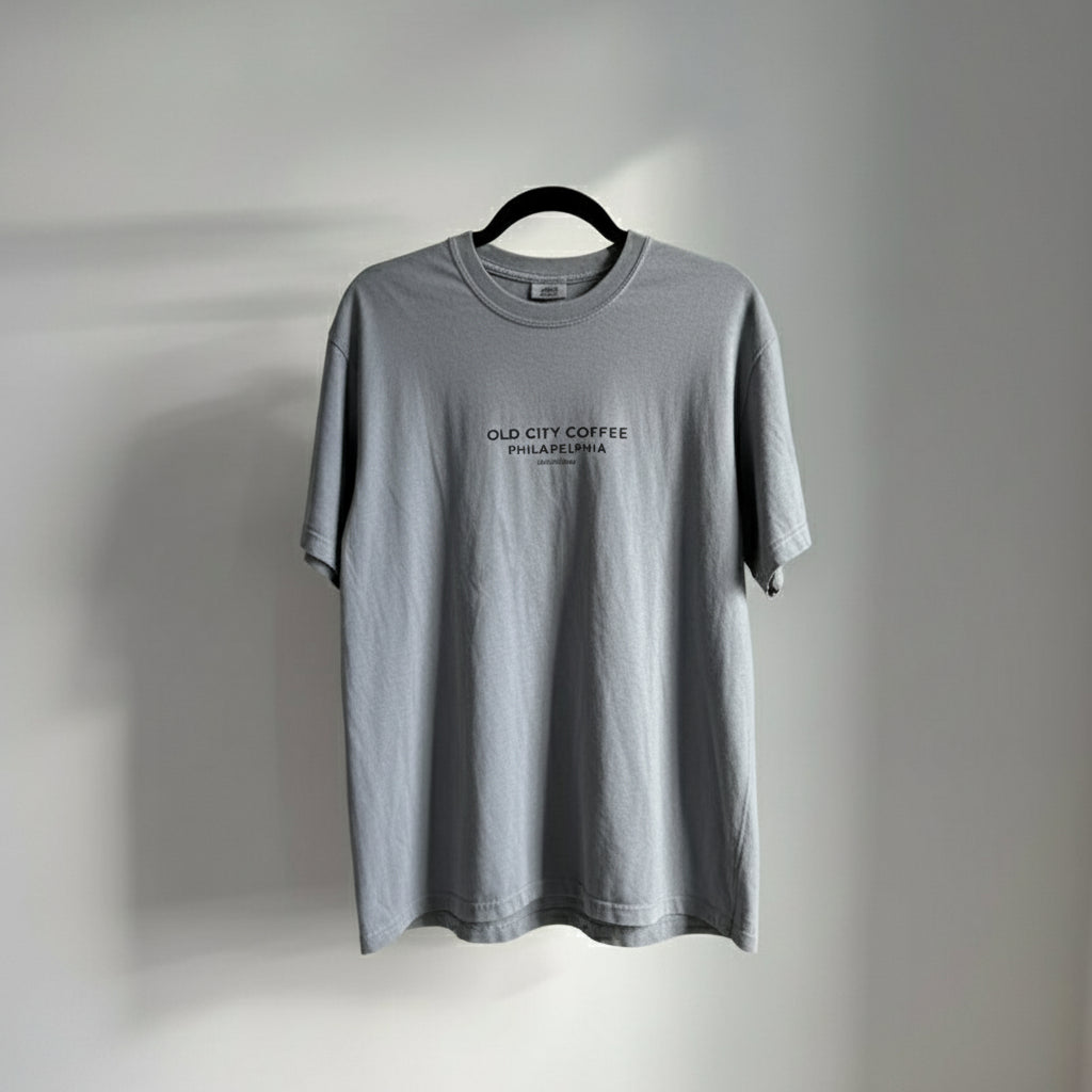 Gray t-shirt with 'Old City Coffee Philadelphia' text on a hanger against a gray background