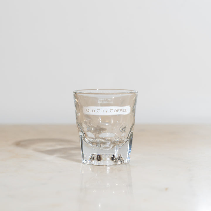 A front view of a 4oz clear Gibraltar glass featuring a white Old City Coffee logo near the rim.