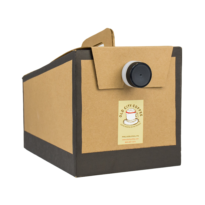 A brown cardboard portable coffee catering box with a black carrying handle and a black pour spout on the front, shown against a transparent background. A square label on the box features the Old City Coffee vintage cup logo, "Coffee Roasted on the Premises," and Philadelphia location details.
