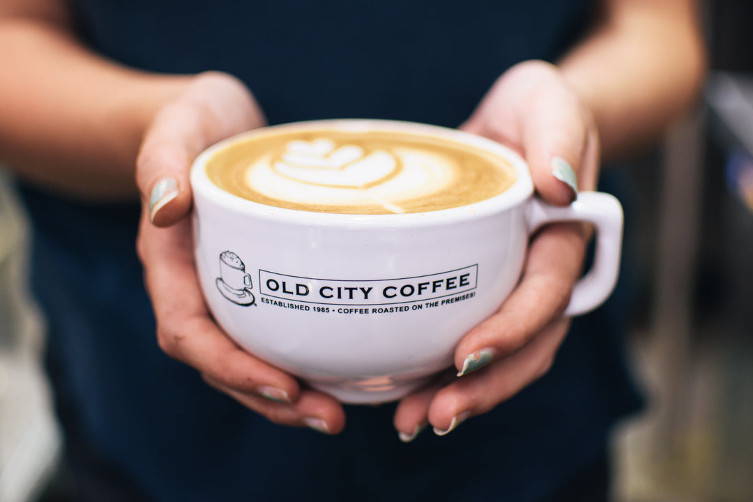 Person holding a cup of coffee with 'Old City Coffee' branding.