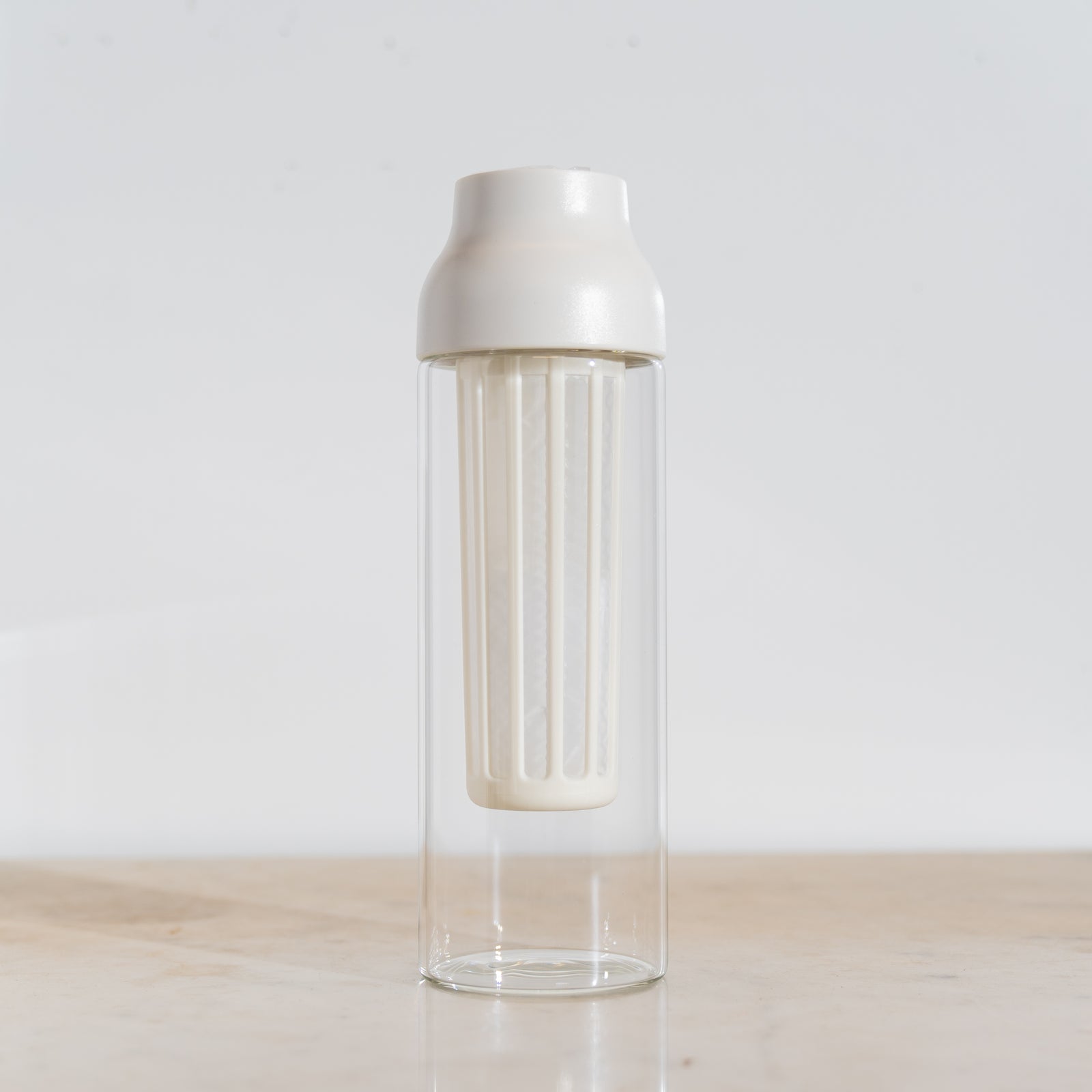 Clear glass bottle with silver lid on a light wooden surface and white background