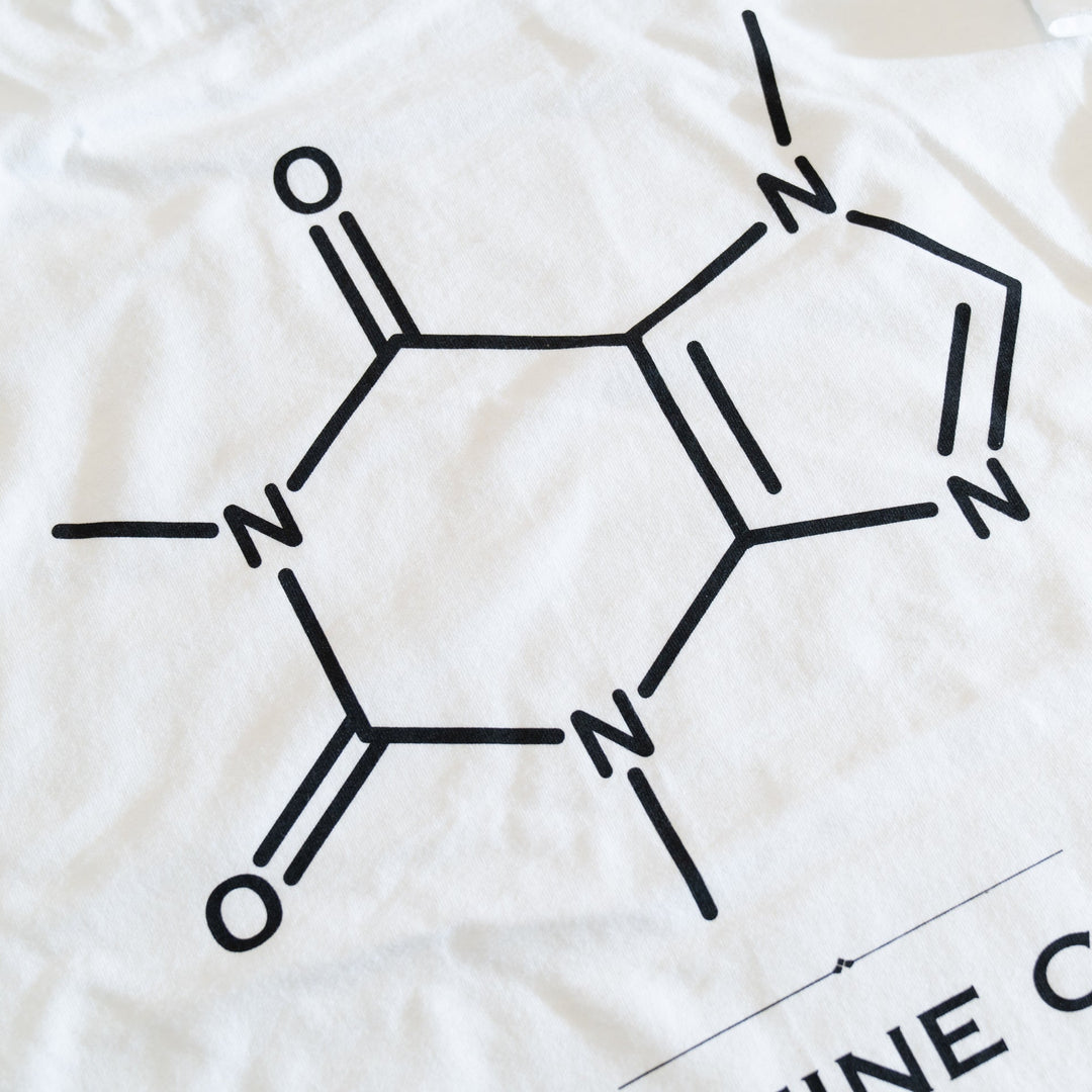 Close-up of the caffeine molecule diagram printed in black on the white T-shirt
