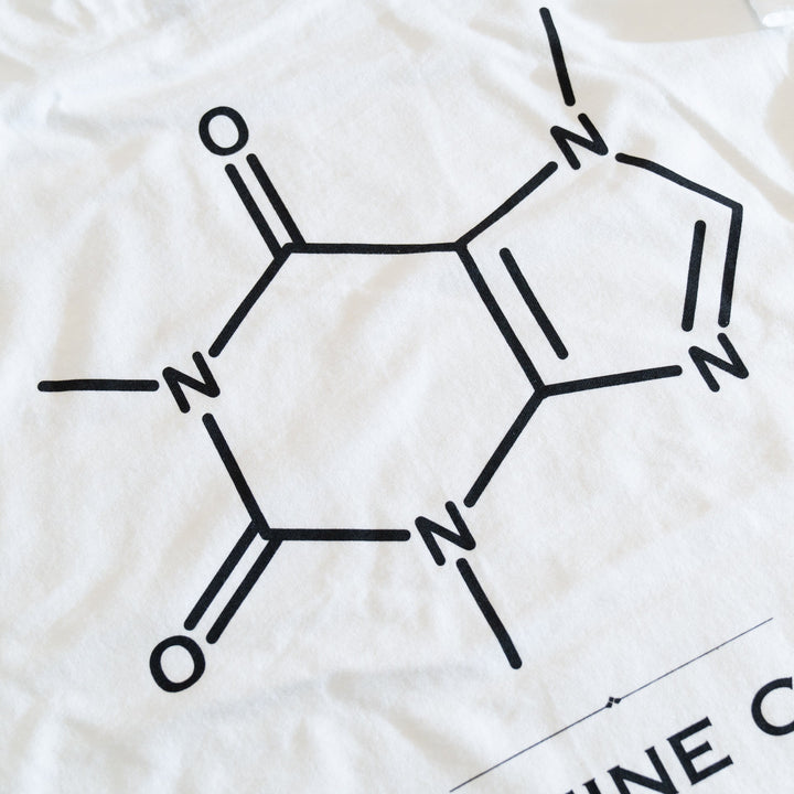 Close-up of the caffeine molecule diagram printed in black on the white T-shirt