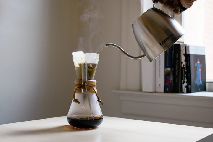 Gooseneck kettle pouring water into a Chemex 3 cup on a desk