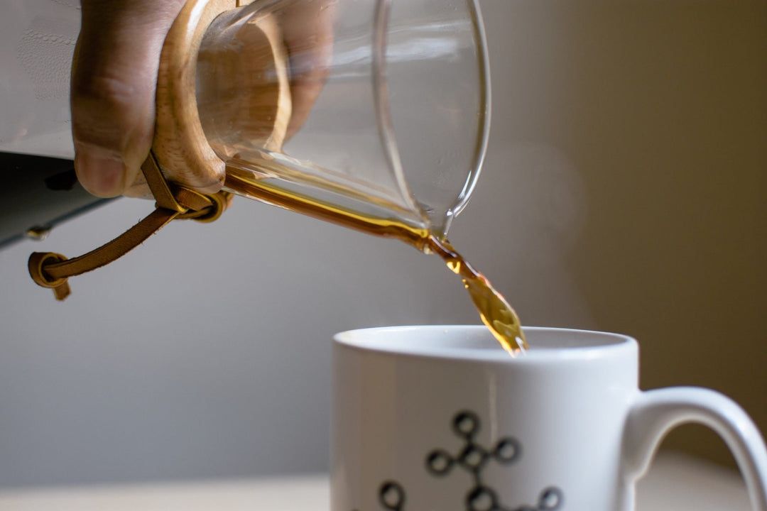 Close-up of coffee pouring from the Chemex spout into a white mug
