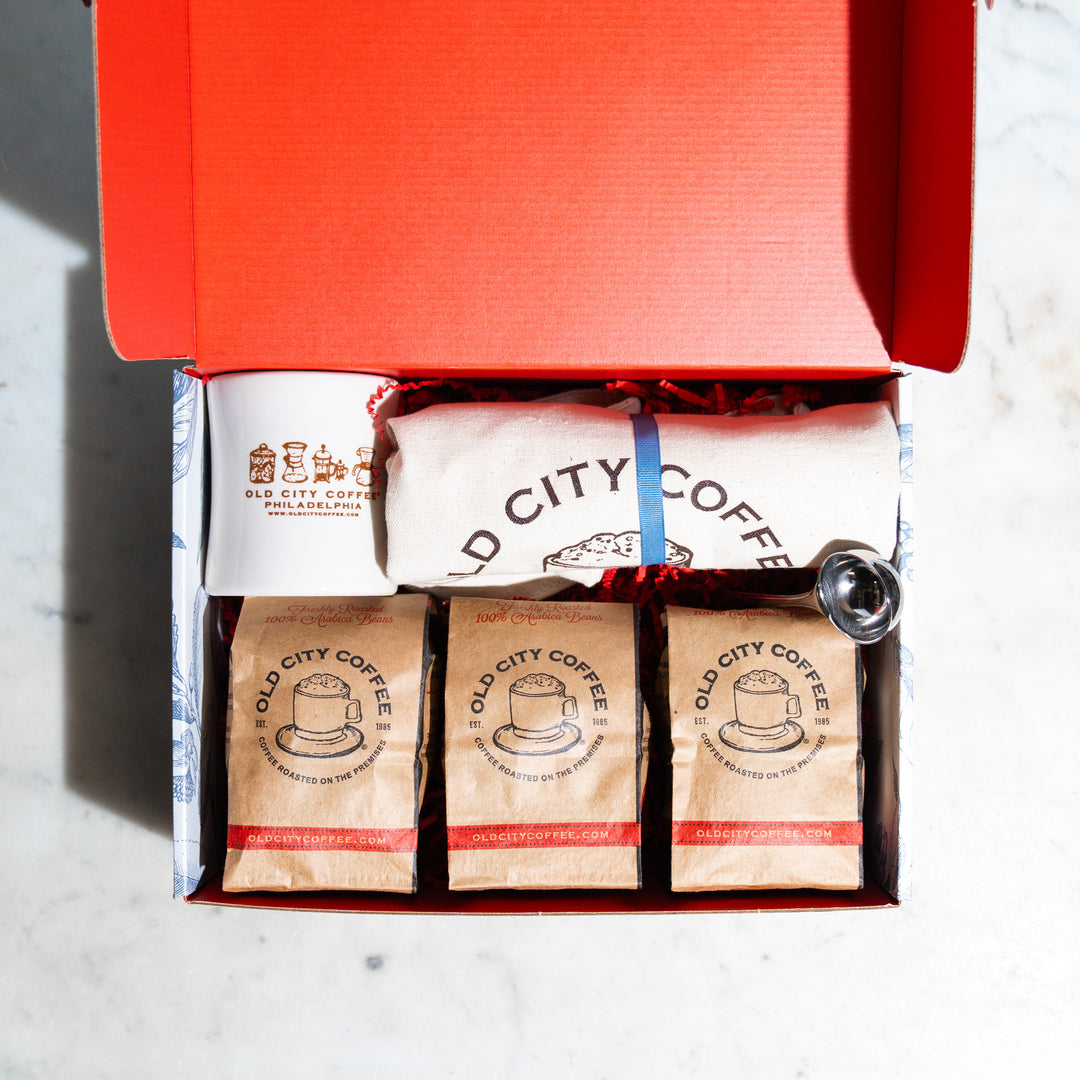 Open red gift box with kraft Old City Coffee bags and a stainless scoop