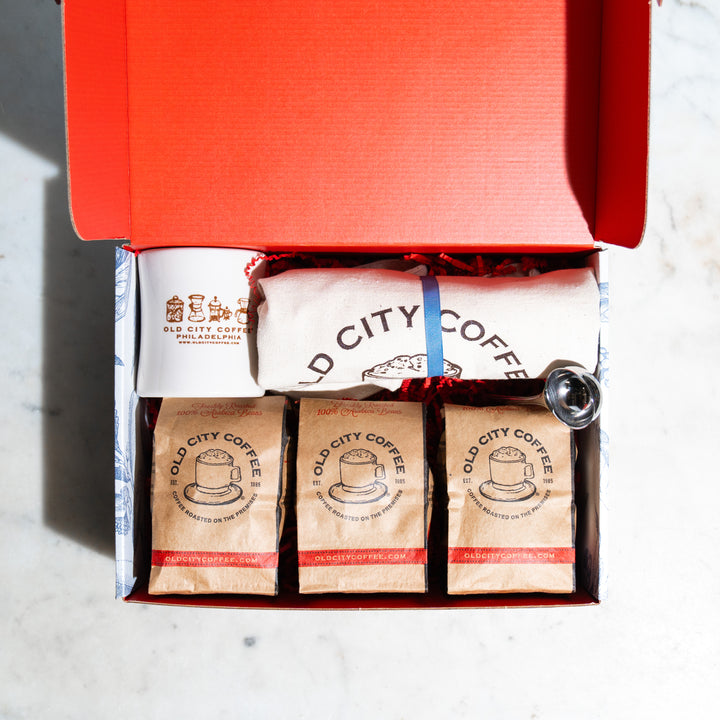 Open red gift box with kraft Old City Coffee bags and a stainless scoop