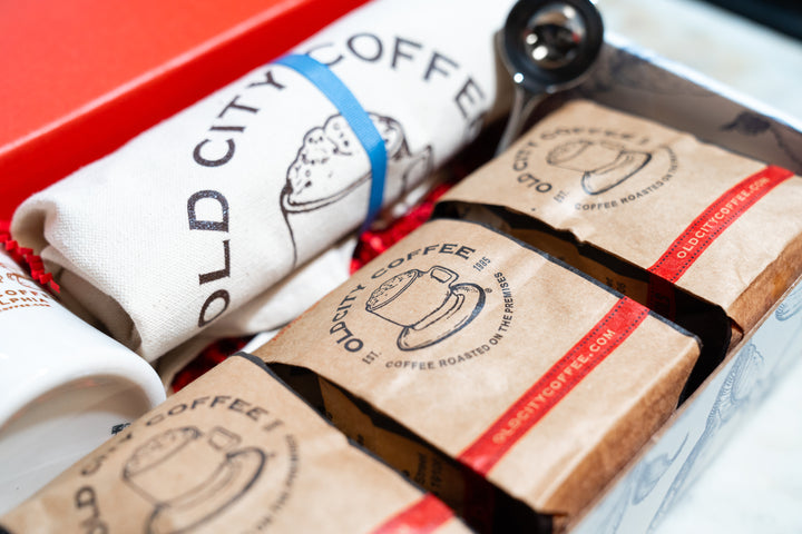 Close-up of kraft coffee bags and the rolled canvas tote inside the gift box