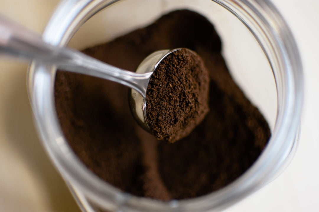 Scoop lifting ground coffee from a container