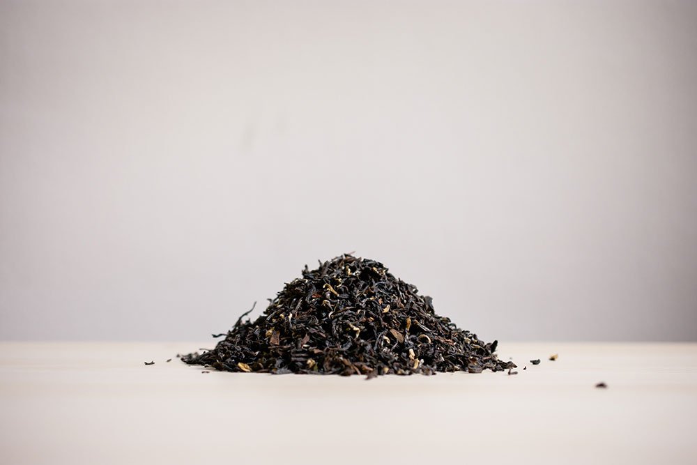 Small pile of loose Darjeeling black tea on a white surface
