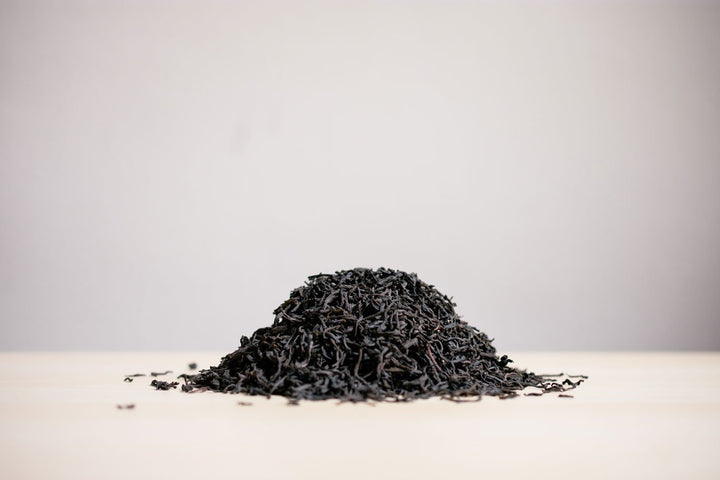 Small pile of loose decaf Ceylon black tea on a white surface