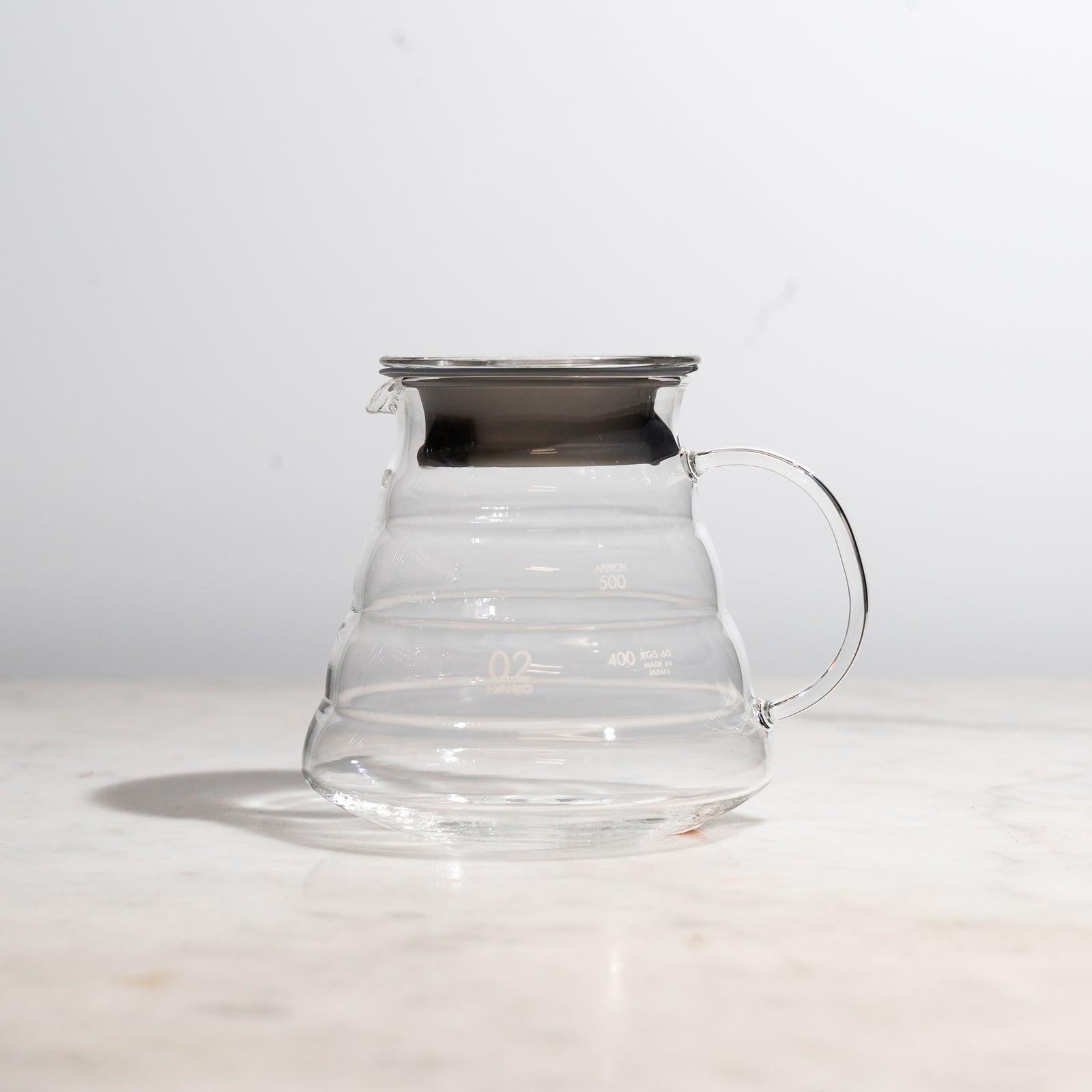 Clear Hario glass carafe with black lid on a marble counter