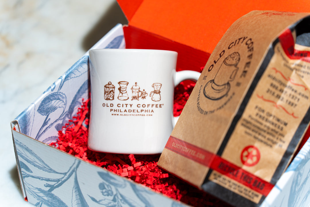 Open gift box with an Old City Coffee diner mug and a kraft bag of coffee nestled in red crinkle paper