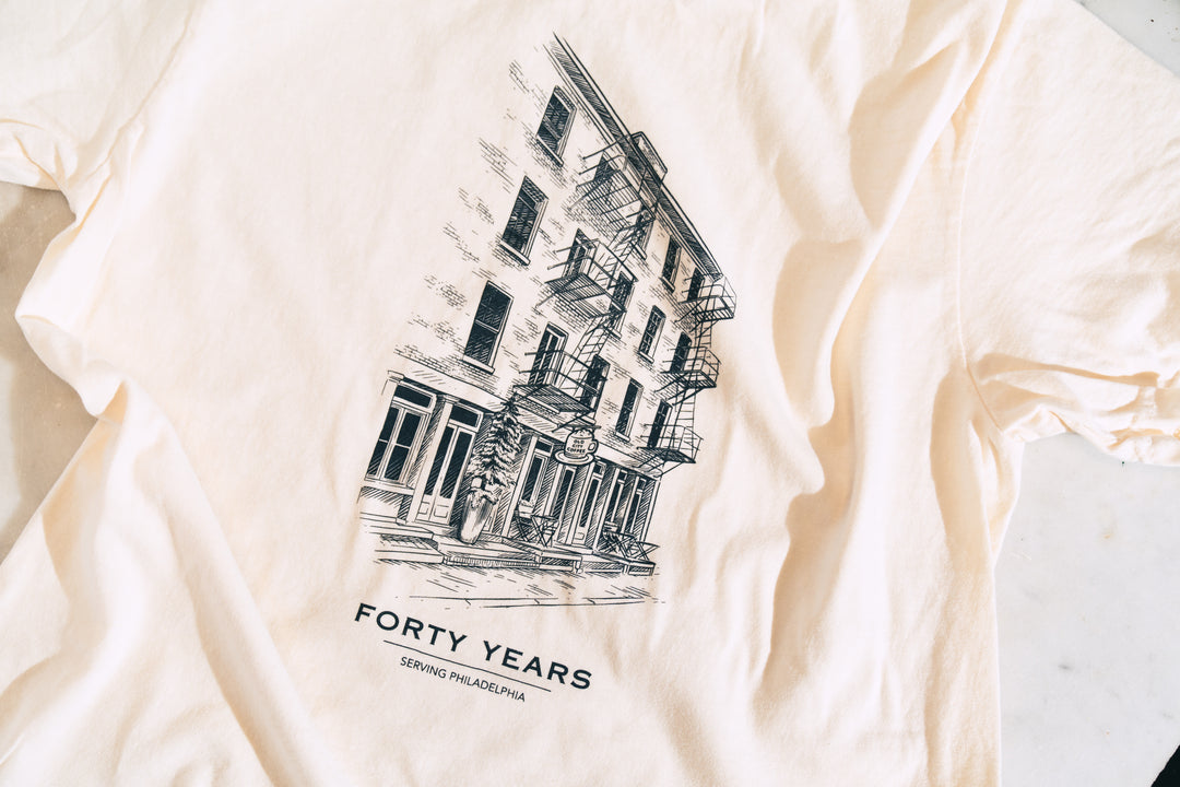 Cream 40th anniversary T-shirt laid flat, back printed with an ink illustration of the Old City Coffee storefront above the words Forty Years