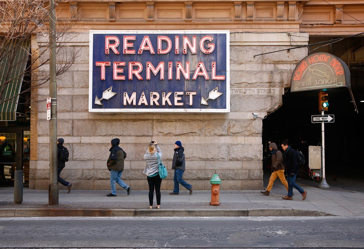 Reading Terminal Market sign above the market entrance in Philadelphia, with pedestrians walking past