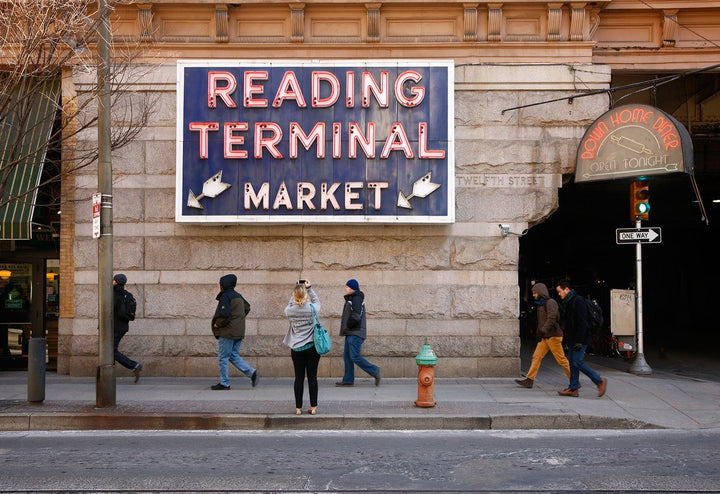 Reading Terminal Market sign above the market entrance in Philadelphia, with pedestrians walking past