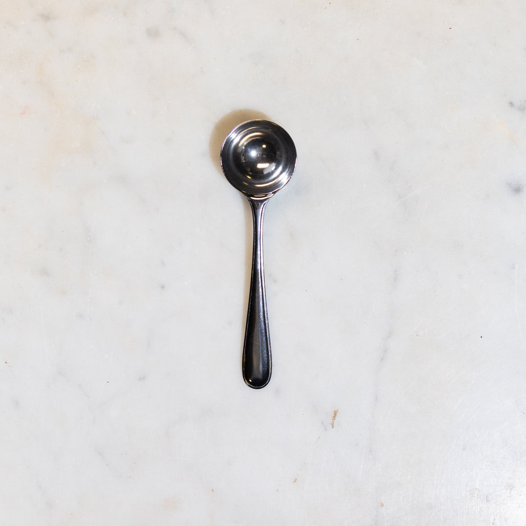 Stainless steel scoop for coffee or tea on a marble counter