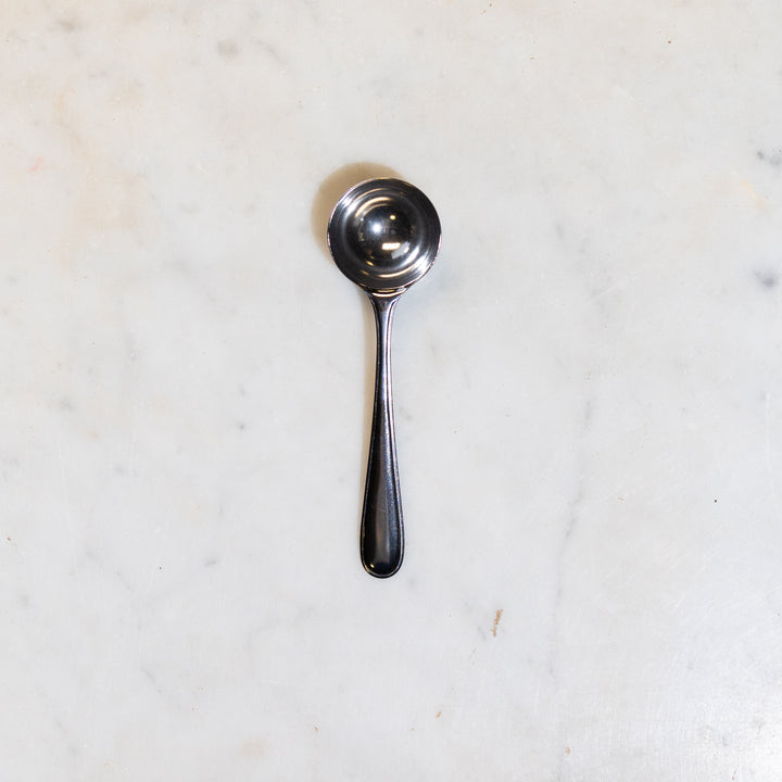 Stainless steel scoop for coffee or tea on a marble counter