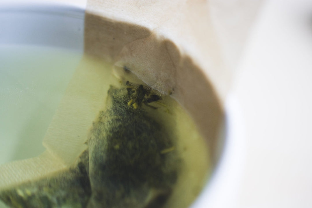 Close-up of loose leaf tea steeping inside a paper filter in a cup