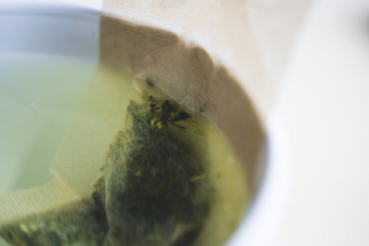 Close-up of loose leaf tea steeping inside a paper filter in a cup