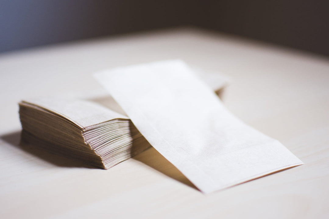 Single paper tea filter propped upright against a stack of filters